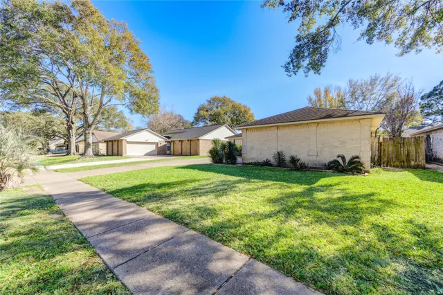 a view of a house with a yard and large trees