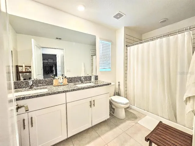 a bathroom with a granite countertop sink toilet and mirror