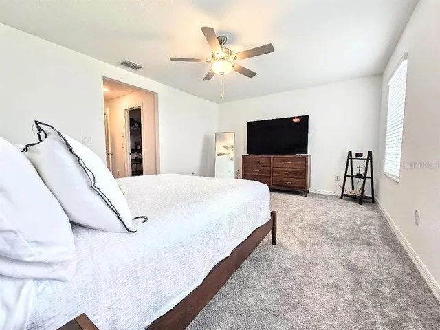 a spacious bedroom with a bed and a flat screen tv