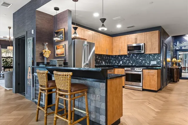 a kitchen with stainless steel appliances kitchen island granite countertop a table chairs and a refrigerator