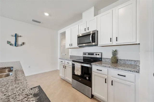 a kitchen with granite countertop white cabinets sink and stainless steel appliances