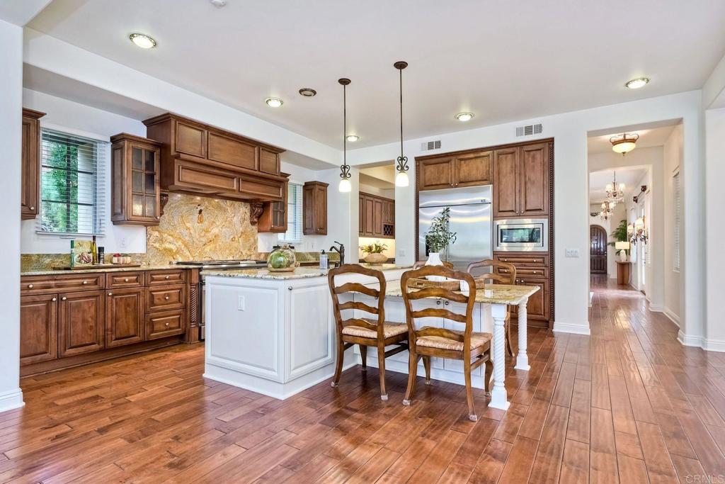 17284 Reflections Circle San Diego, CA 92127 - Photo 16 of 53 a kitchen with stainless steel appliances kitchen island granite countertop a stove a refrigerator a sink a dining table and chairs with wooden floor