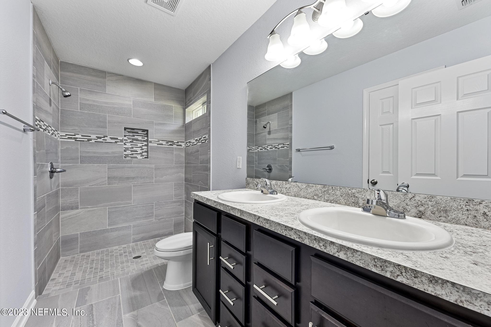 4118 Spring Park Circle Jacksonville, FL 32207 - Photo 15 of 21 a bathroom with a granite countertop sink a toilet a mirror and shower