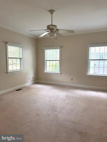 an empty room with a windows and chandelier fan
