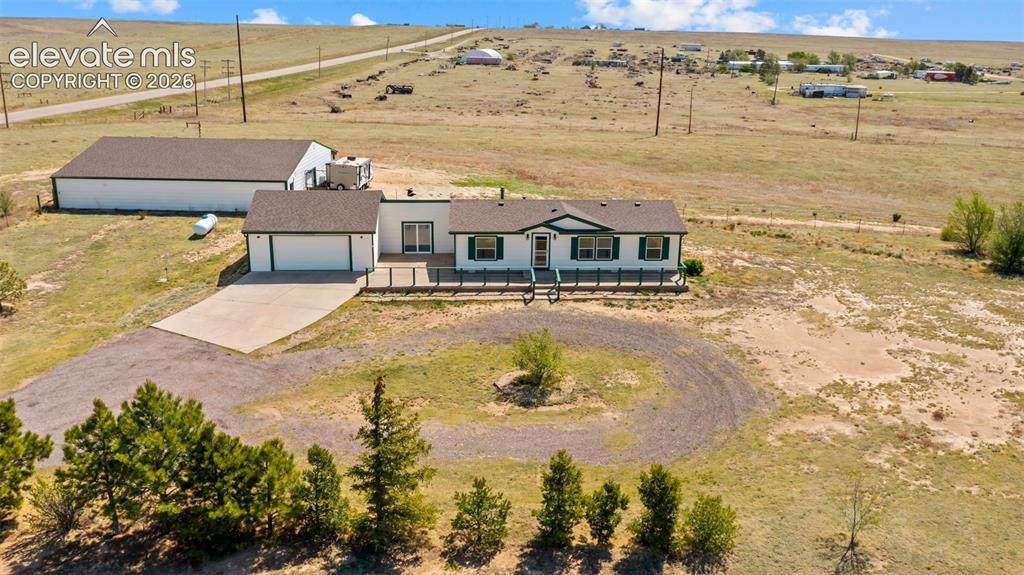 33975 Highway 94 Yoder, CO 80864 - Photo 27 of 40 Ranch-style residence featuring an attached two-car garage, a substantial detached outbuilding, and a gravel circular driveway