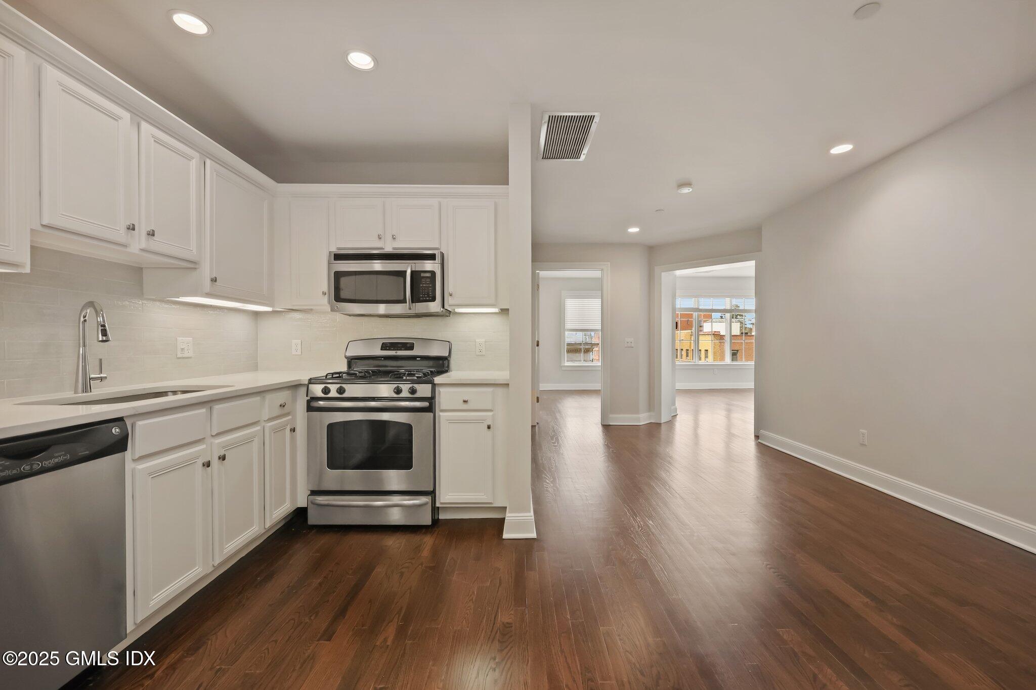 2 East Elm Street, Unit 42 Greenwich, CT 06830 - Photo 7 of 24 a kitchen with granite countertop a stove top oven a sink dishwasher and a refrigerator with wooden floor