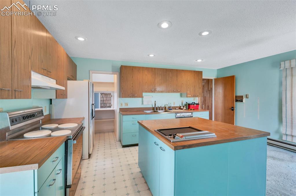 24975 Sanborn Road Calhan, CO 80808 - Photo 14 of 50 a kitchen with kitchen island stainless steel appliances a sink stove and refrigerator