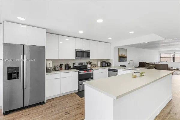 a kitchen with a refrigerator a stove top oven a sink and cabinets