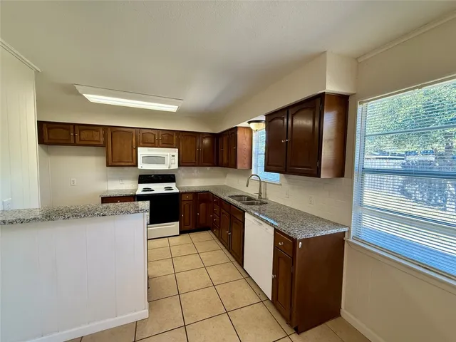 a large kitchen with granite countertop a sink and cabinets