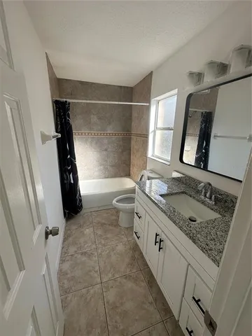 a bathroom with a granite countertop sink a washing machine and a shower