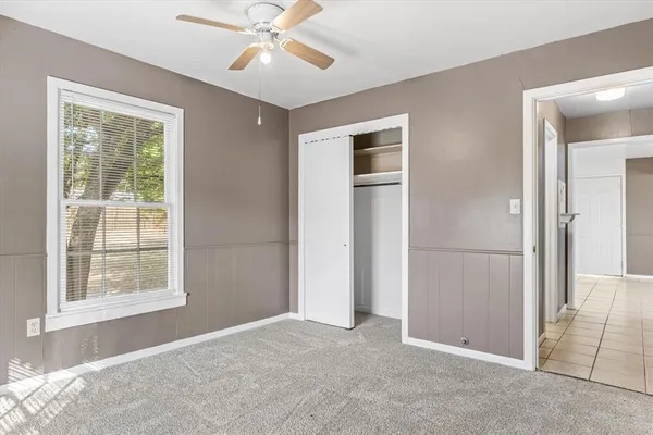 an empty room with chandelier fan and windows