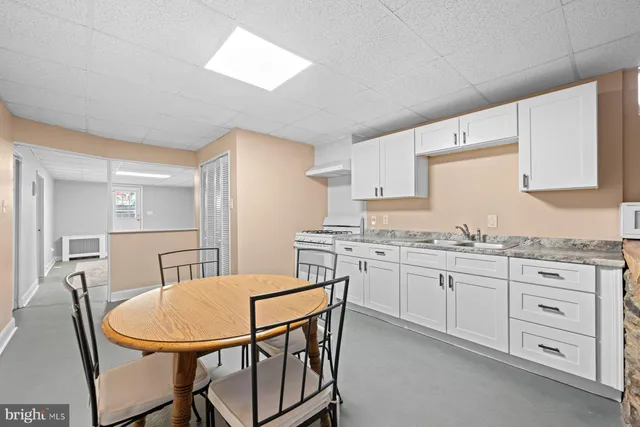 an empty room with chandelier fan and windows