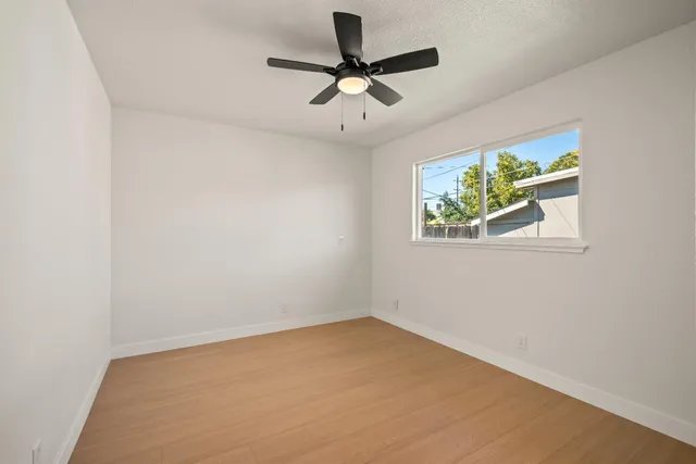 an empty room with a window and a ceiling fan