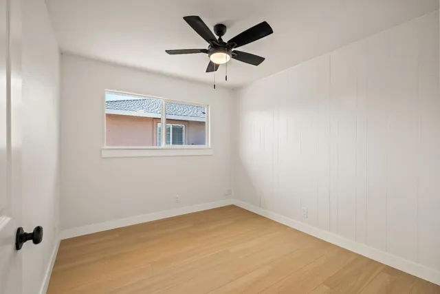 an empty room with a window and a ceiling fan