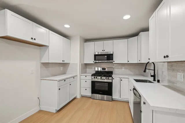 a kitchen with white cabinets sink and stainless steel appliances