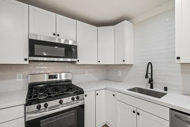a kitchen with white cabinets and appliances