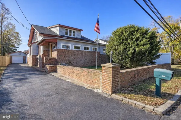 a front view of a house with large trees