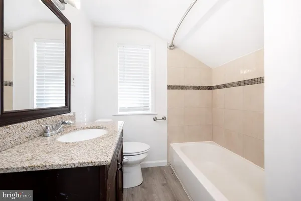 a bathroom with a granite countertop sink a toilet and bathtub