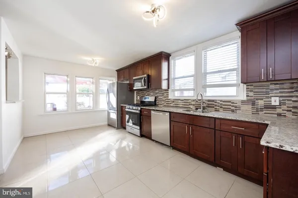 a kitchen with granite countertop a stove a sink and a refrigerator