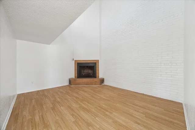 a view of an empty room with wooden floor and a fireplace