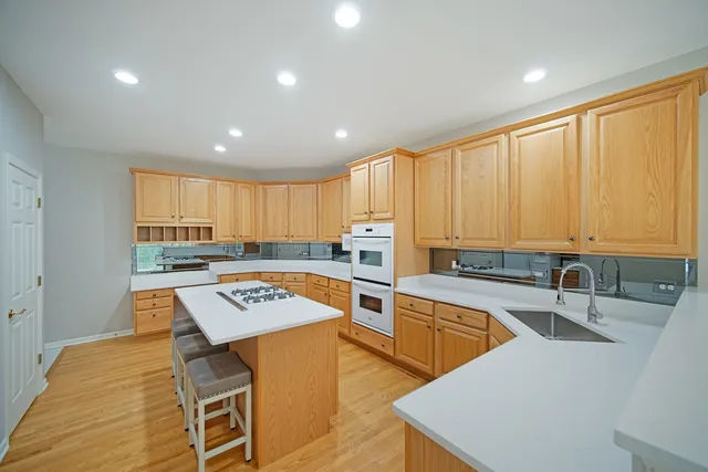 a view of a kitchen with kitchen island stainless steel appliances a sink and cabinets