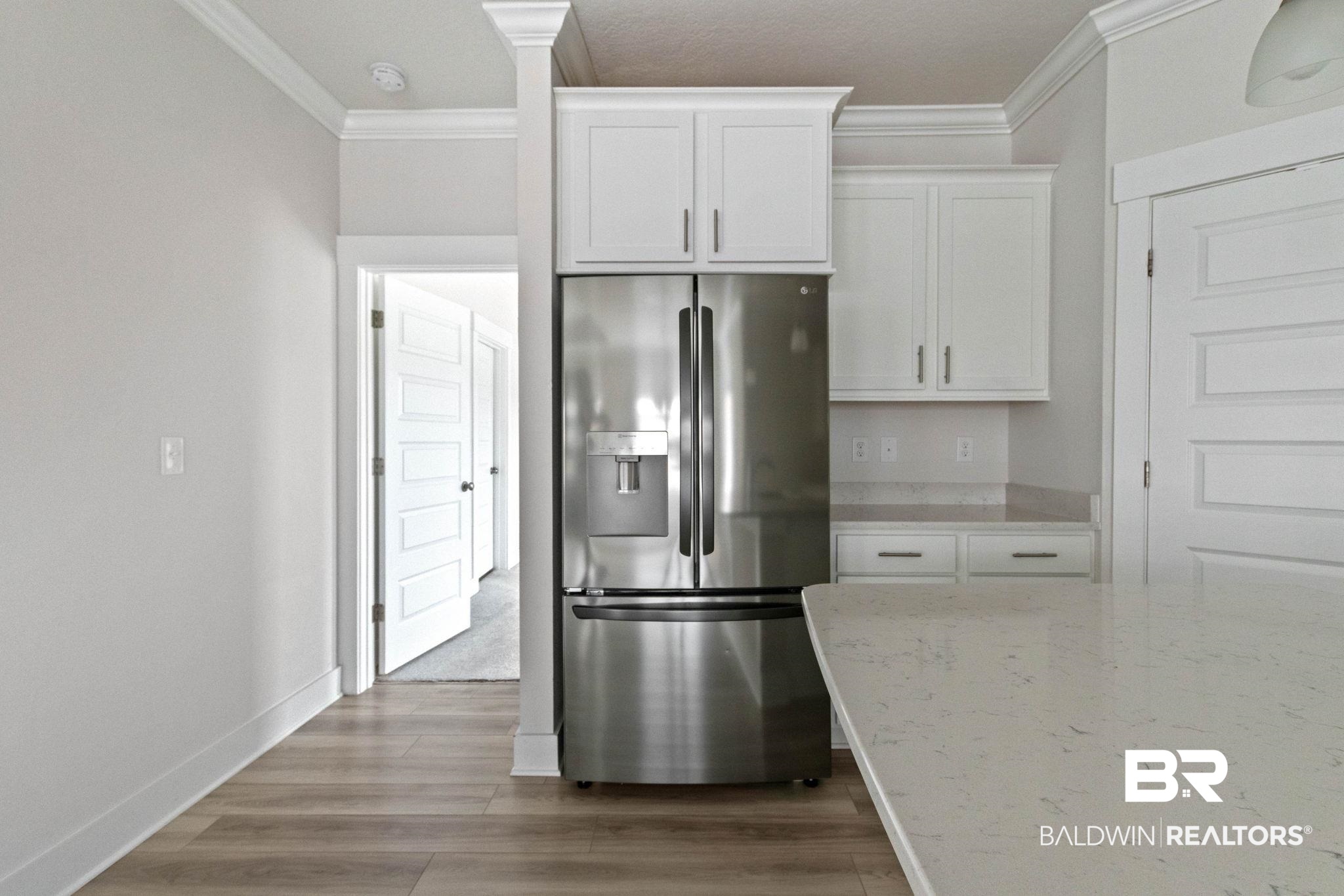 1710 Grouse Street Foley, AL 36535 - Photo 33 of 76 Modern kitchen featuring a stainless steel French door refrigerator, white shaker cabinetry, light-toned countertops, and wood-finish flooring