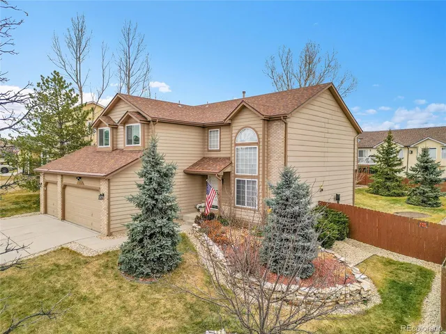 a front view of a house with a garden and trees