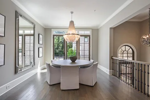 a dining room with wooden floor chandelier and windows