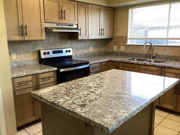 a kitchen with granite countertop a sink a stove and cabinets