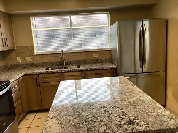 a kitchen with granite countertop a refrigerator and a sink