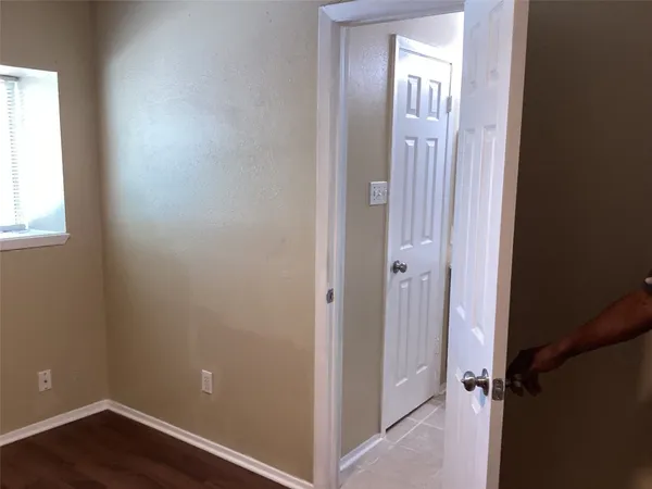 an empty room with wooden floor mirror and windows