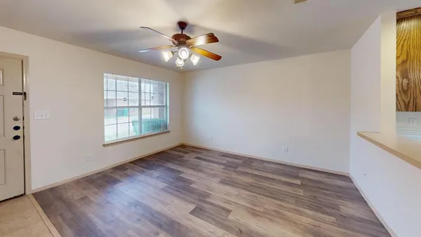 a view of an empty room with wooden floor and a window