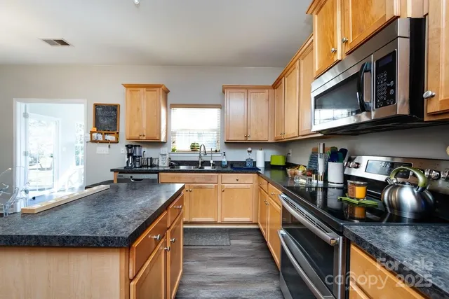 a kitchen with stainless steel appliances granite countertop a stove a sink and a microwave
