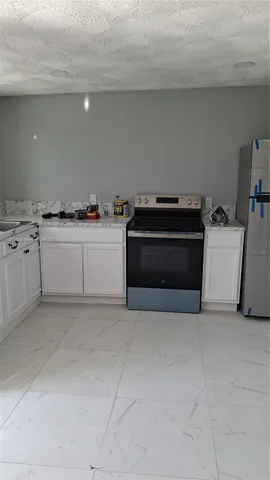 a kitchen with stainless steel appliances a stove and white cabinets