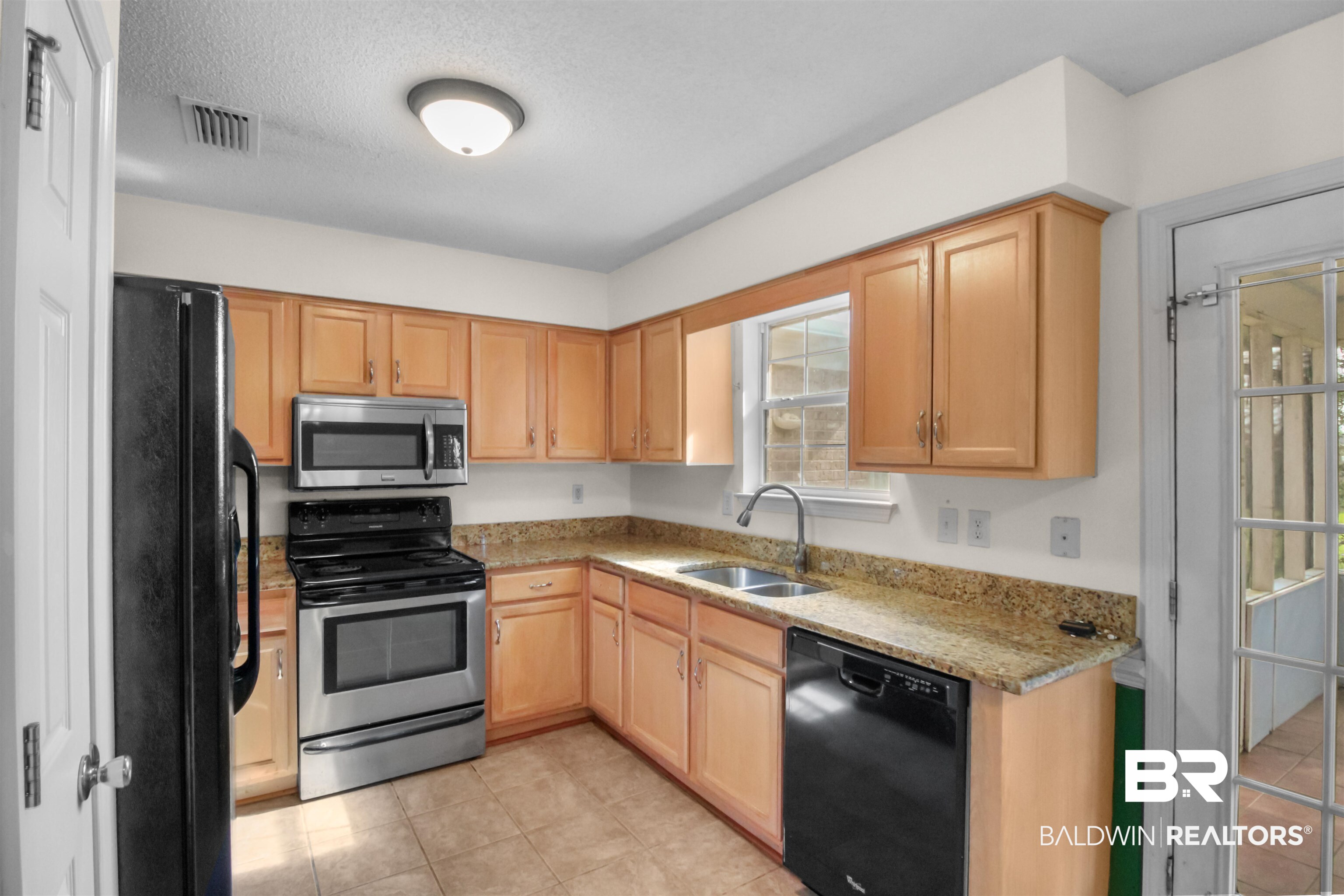 8940 Caitlin Street Foley, AL 36535 - Photo 2 of 27 Kitchen with black appliances, light stone counters, light wood finish cabinets, light tile patterned floors, and a textured ceiling