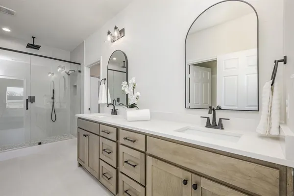 a bathroom with a double vanity sink mirror and shower