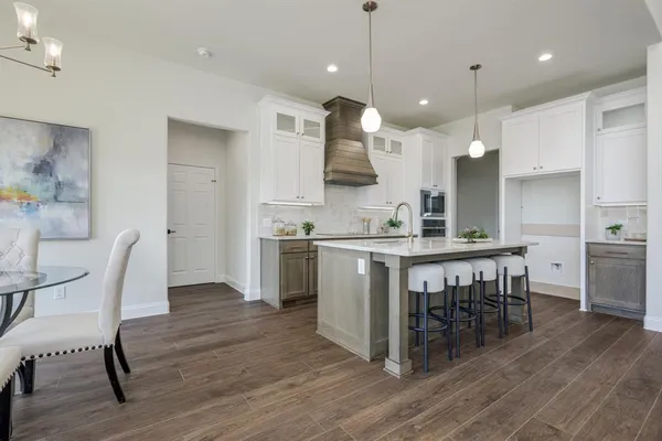 a kitchen with kitchen island a dining table chairs sink and wooden floor