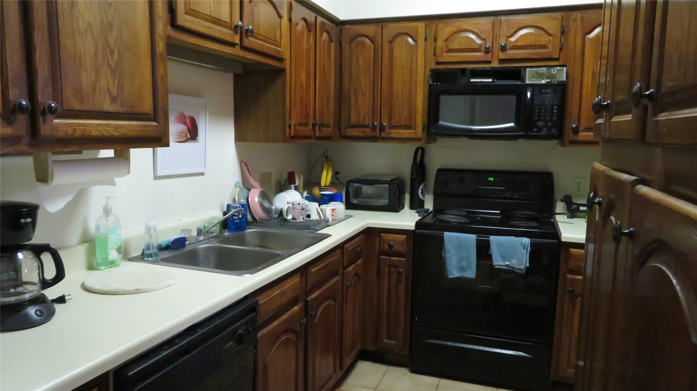 1910 Robbins Place, Unit 202 Austin, TX 78705 - Photo 3 of 15 Kitchen with black appliances, light countertops, light tile patterned flooring, and brown cabinetry