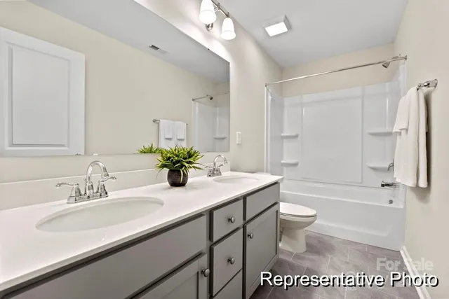 a bathroom with a granite countertop sink a toilet a mirror a bathtub and shower