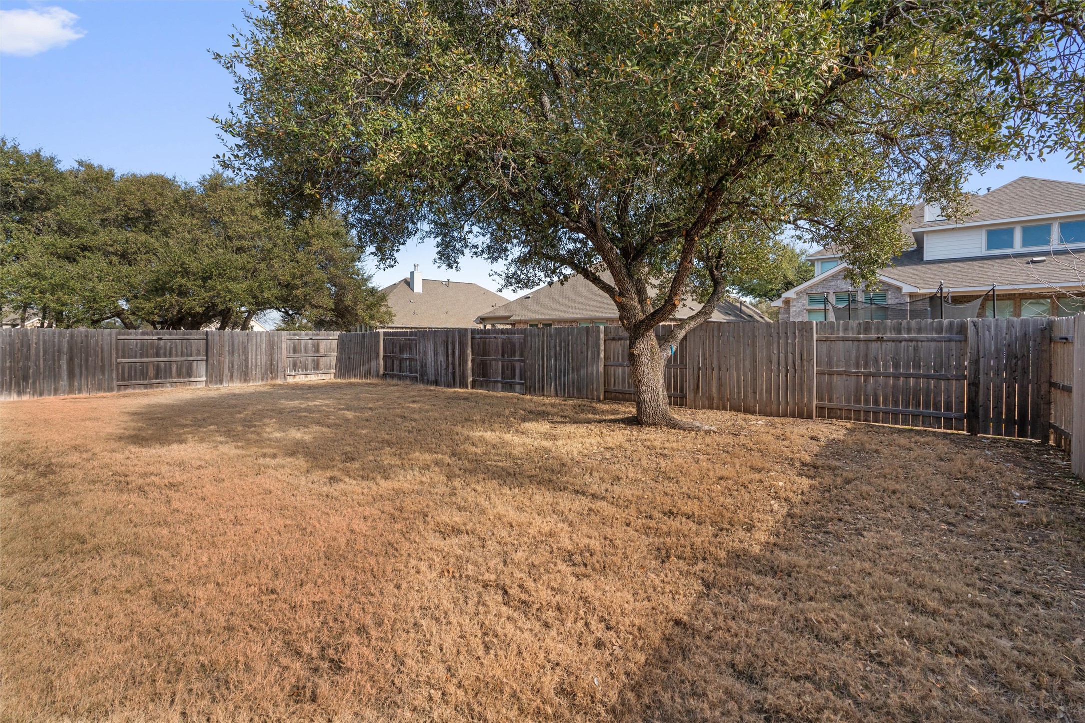 109 Wake Lane Georgetown, TX 78633 - Photo 30 of 34 a backyard of a house with large trees and wooden fence