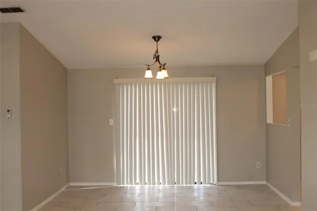 an empty room with chandelier fan and windows