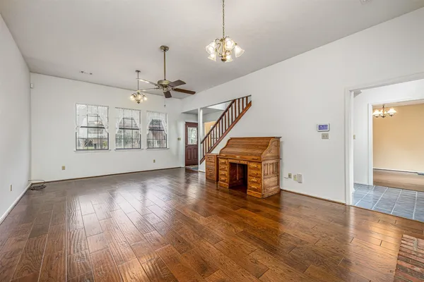 a view of an empty room with wooden floor staircase and a kitchen