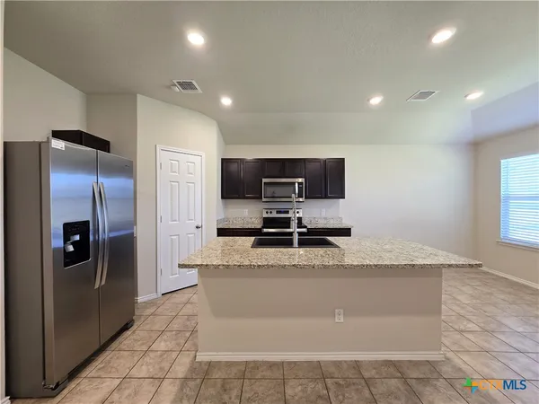 a large kitchen with granite countertop a large counter top stainless steel appliances and a sink
