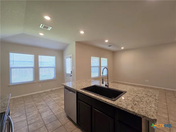a kitchen with granite countertop a sink stove and cabinets