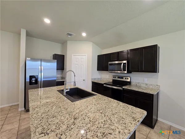 a kitchen with stainless steel appliances granite countertop a sink refrigerator and microwave