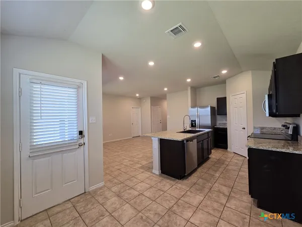 a kitchen with stainless steel appliances granite countertop a refrigerator and a stove top oven