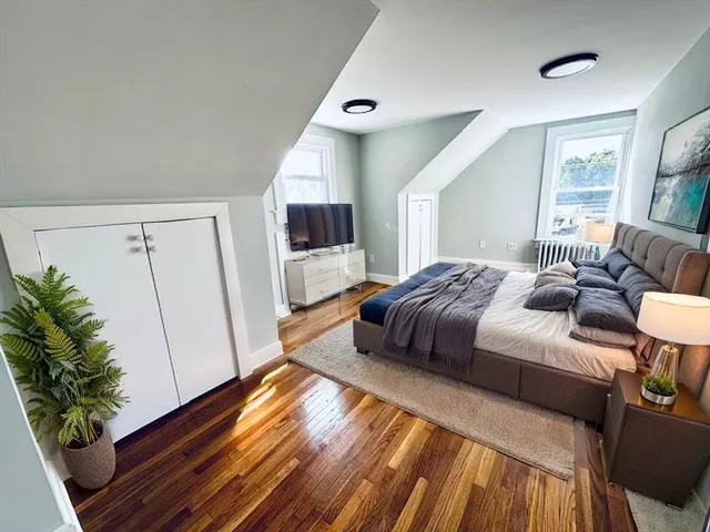 a bedroom with a bed and a potted plant on the dresser