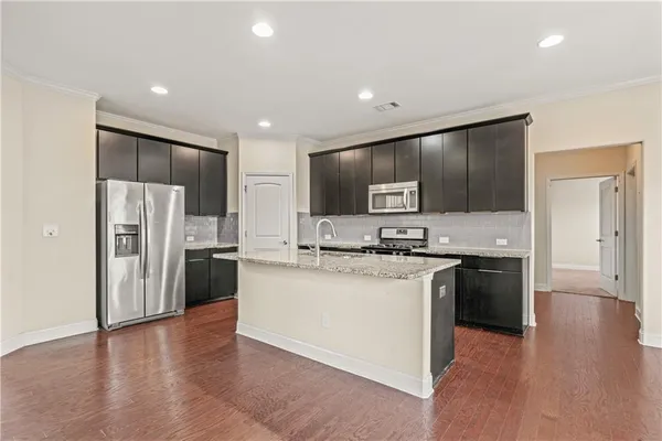 a kitchen with stainless steel appliances granite countertop a refrigerator and a stove top oven