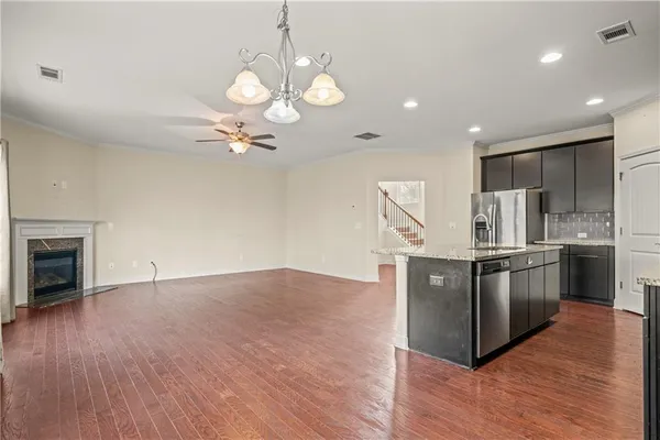 a kitchen with stainless steel appliances granite countertop a sink a stove a refrigerator cabinets and wooden floor
