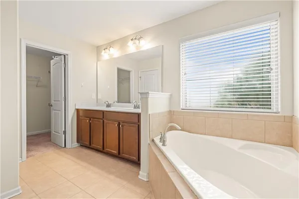 a bathroom with a granite countertop tub sink and mirror